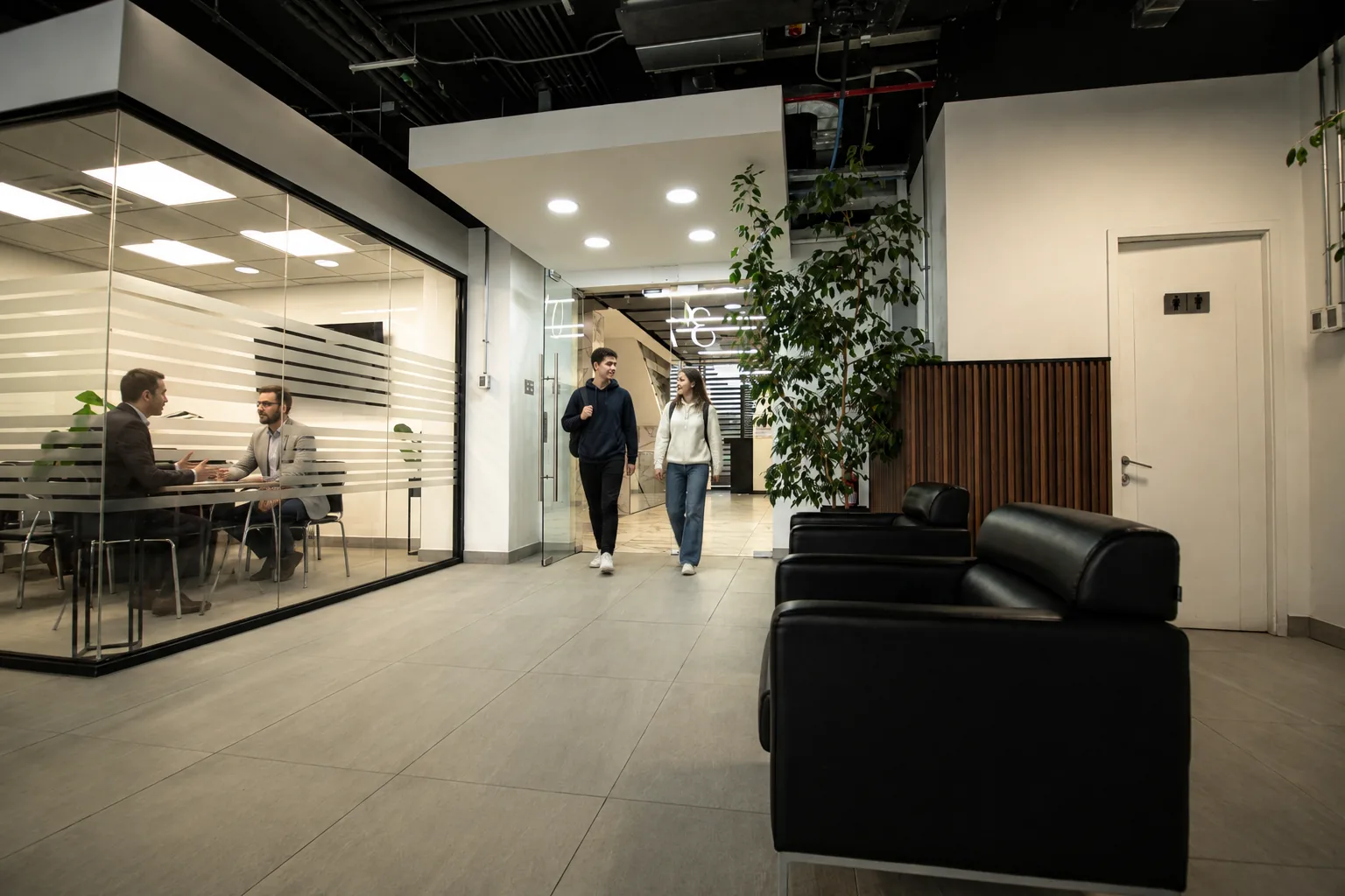 Personas caminando por el lounge junto a una reunión en curso